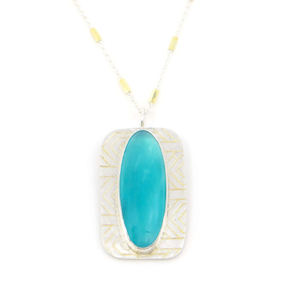 Bezel set oval amazonite on curved silver rectangle etched with geometric pattern. 18k gold added to pattern recesses. 16" silver and gold chain.
