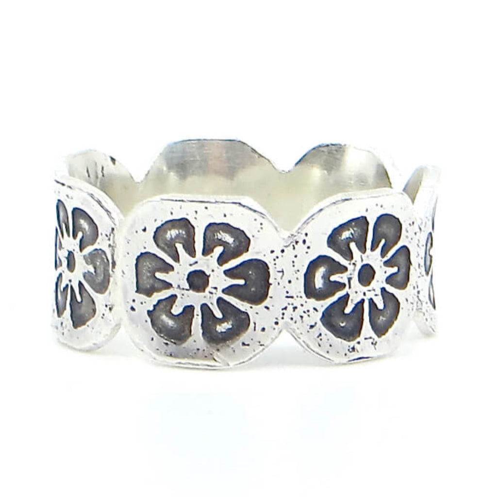 Etched sterling silver ring with flower pattern all around. Rounded attached octagonal sections each with an oxidized flower. Ring is flared slightly. Edgy fine contemporary band. US size 8