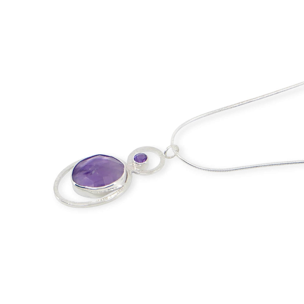 Bezel set rose cut oval atomic amethyst and tube set round faceted amethyst. Each in a textured sterling frame to make a single pendant. Suspended from 16" sterling snake chain.