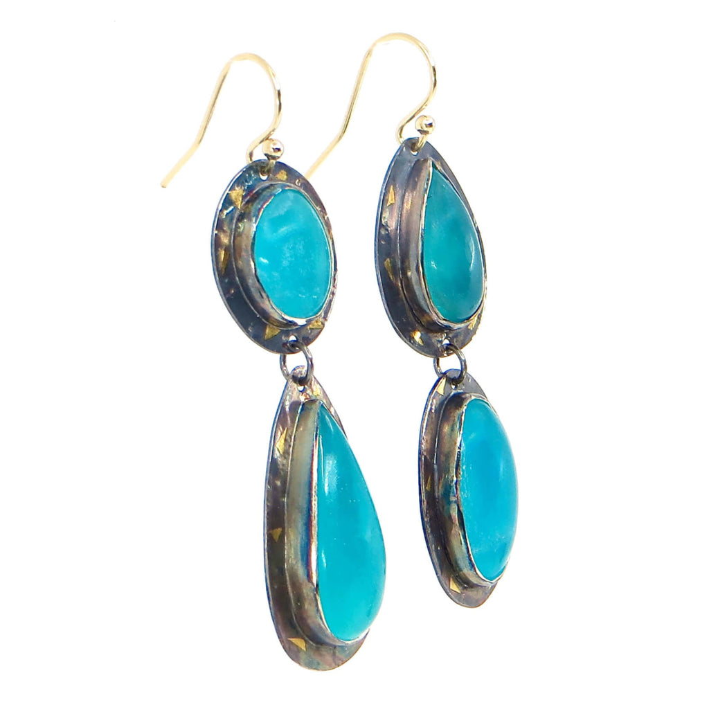 Oval and pear shaped cabochon amazonites of vivid turquoise blue earrings. Oval dangles a pear and pear dangles an oval for opposite placed components. Bezel set stones on sterling silver backings with pieces of 24k gold arranged around the settings. A black patina provides the perfect contrast. Dangle earrings. 2.25"
