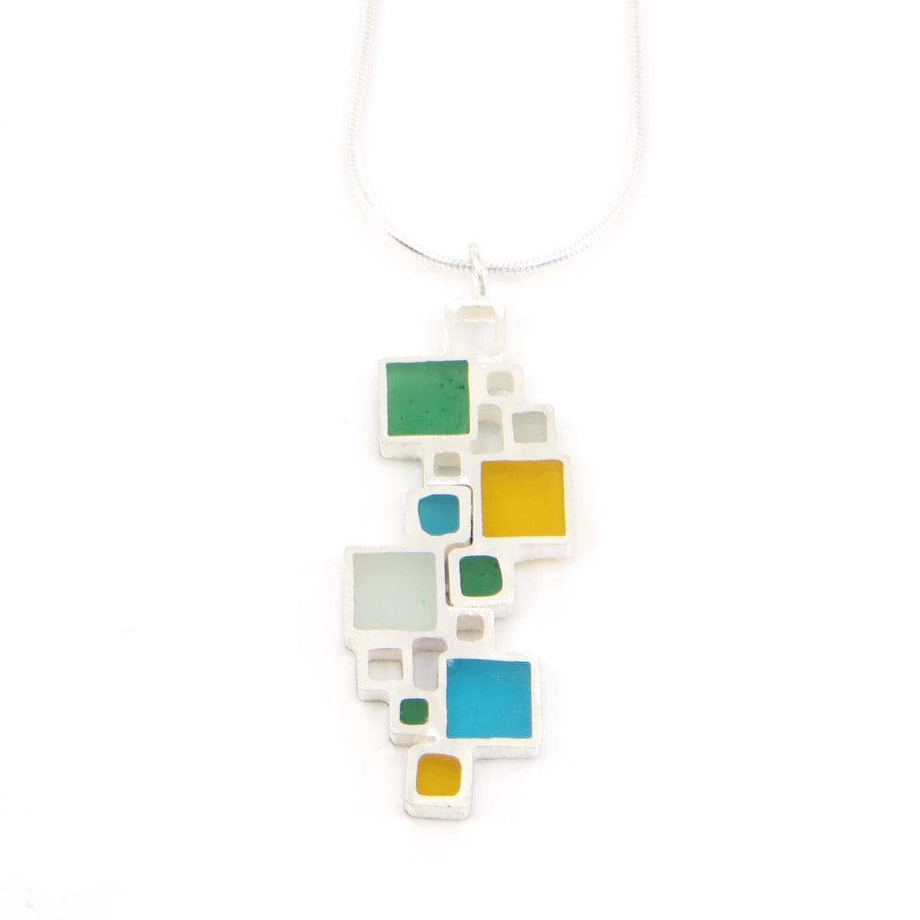 Colorful geometric pendant necklace on a white background. Sterling silver squares, some open, some filled with color.
