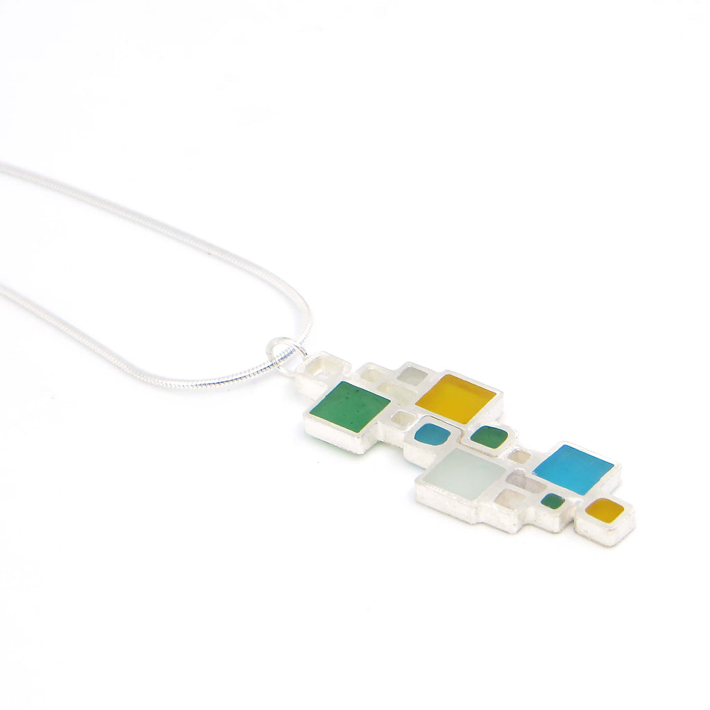 Colorful geometric pendant necklace on a white background. Sterling silver squares, some open, some filled with color.