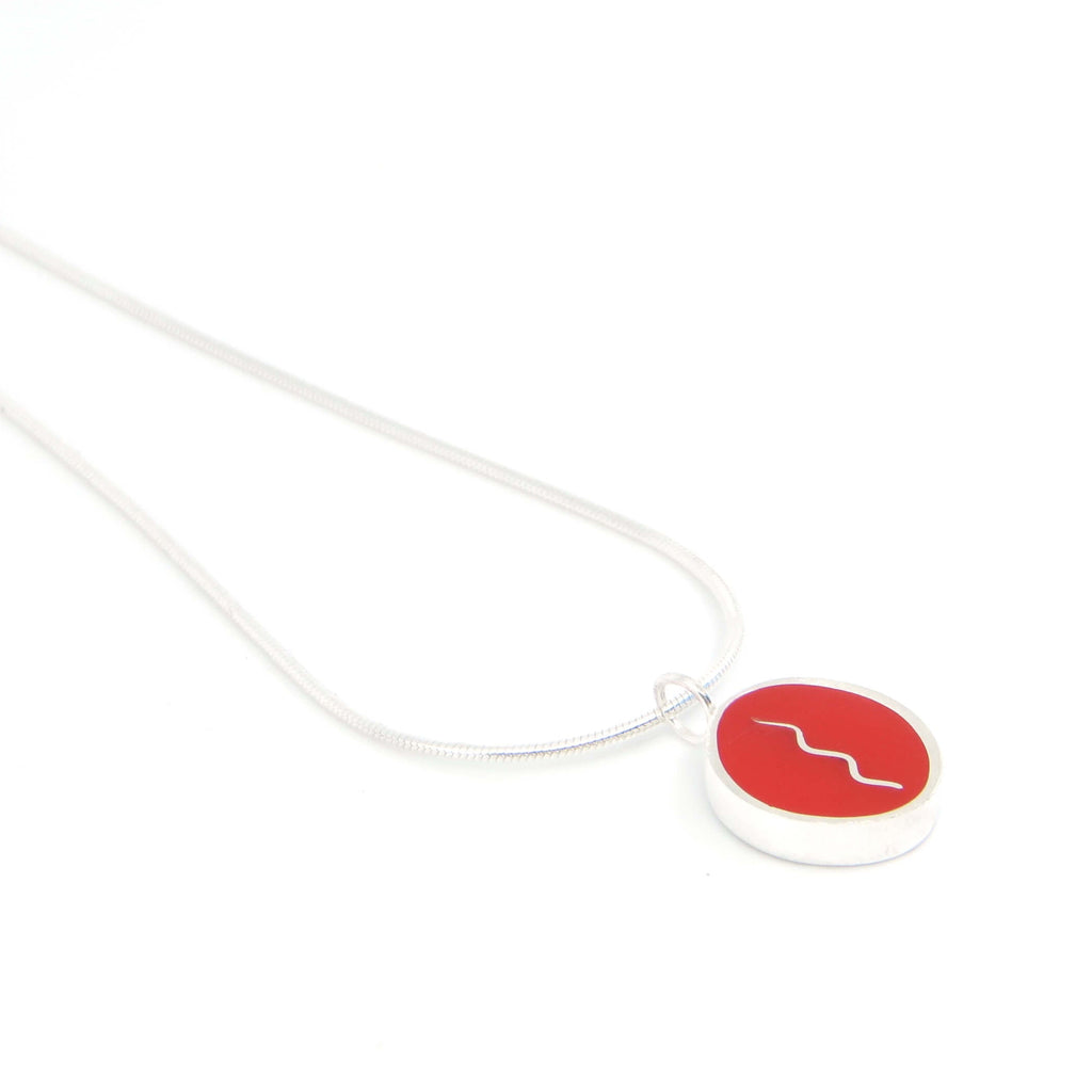 Sterling silver oval pendant with vertical center squiggle. Red.