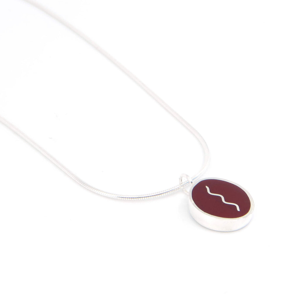 Sterling silver oval pendant with vertical center squiggle. Maroon.