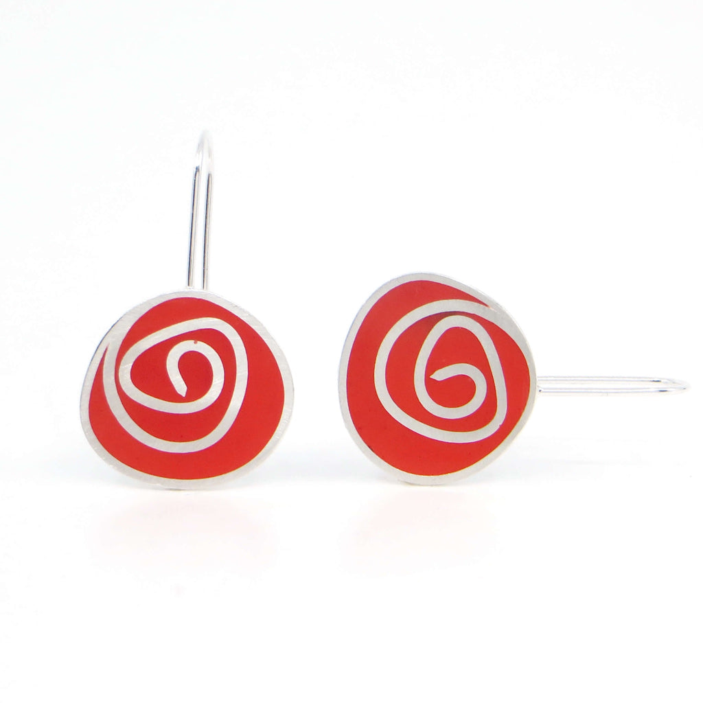 Sterling silver dangle earrings with swirl pattern. Resin pigmented with red chalk pastel fills the receptacles between the swirl pattern and is sanded down flush with the silver.
