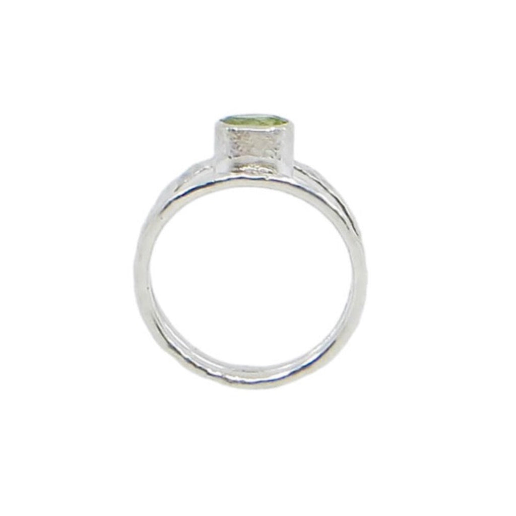 A faceted oval peridot is set east-west in a tube setting hugged on either side by hammered sterling silver bands. The bands taper down towards the center at bottom of ring. Shimmery, airy, fine, contemporary. US size 5.75 could be sized up to size 6.