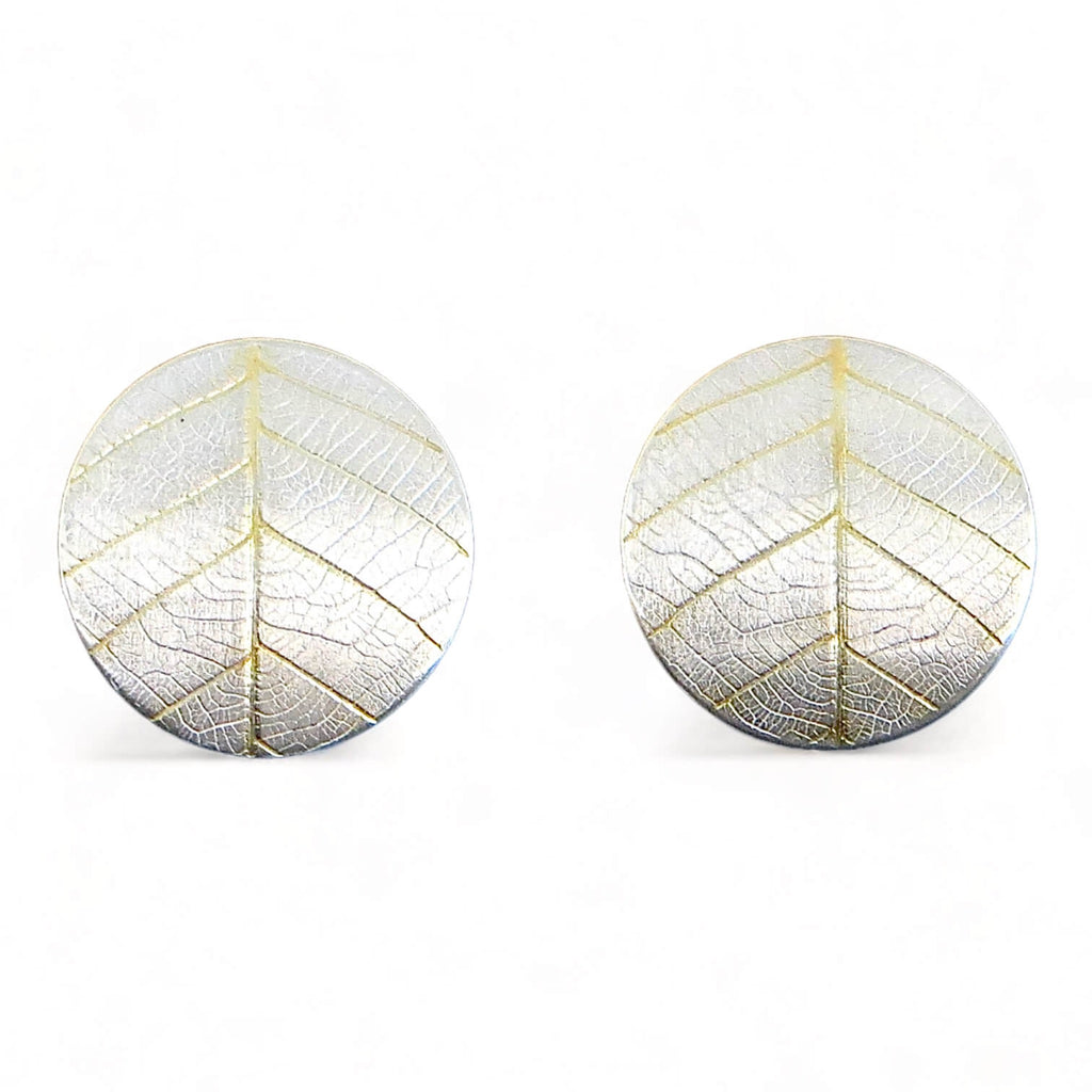 Leaf textured 1" round post silver earrings with 18k gold in the vein recesses. The leaf impression resembles a peace sign.