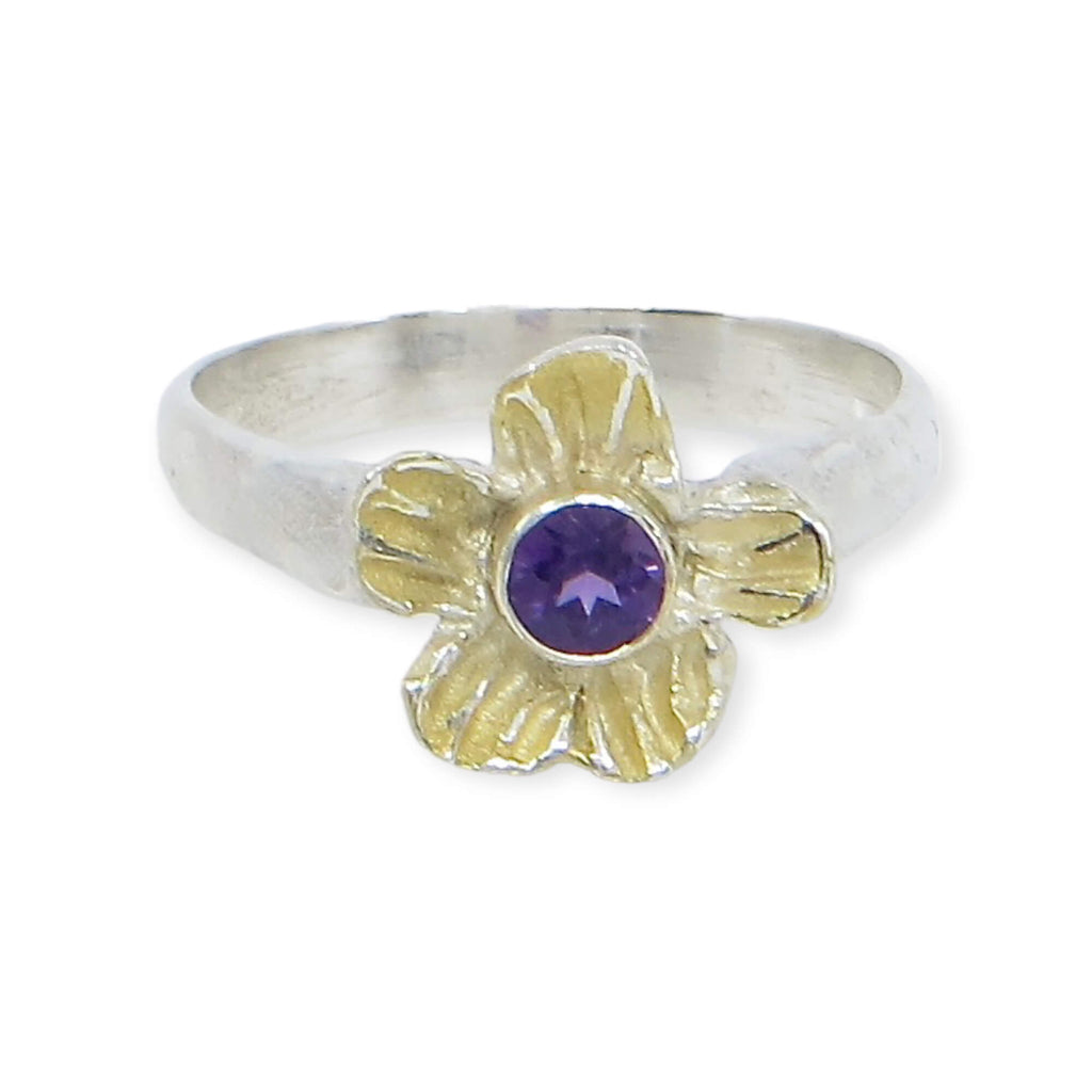 A dimensional textured flower has a center tube set faceted amethyst. A sterling silver ring band golds the sterling flower embellished with 18k gold. Royal colors on a chunky cool flower ring. US Size 6