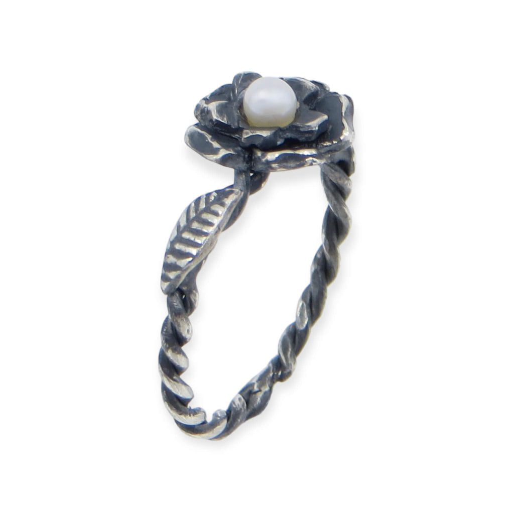 Two layers of different size flower curve upwards surrounding a sweet white pearl. A twisted wire ring band featured carved leaves on either side of the flower. A black patina provides a contrast to the silver and pearl. US Size 7.25