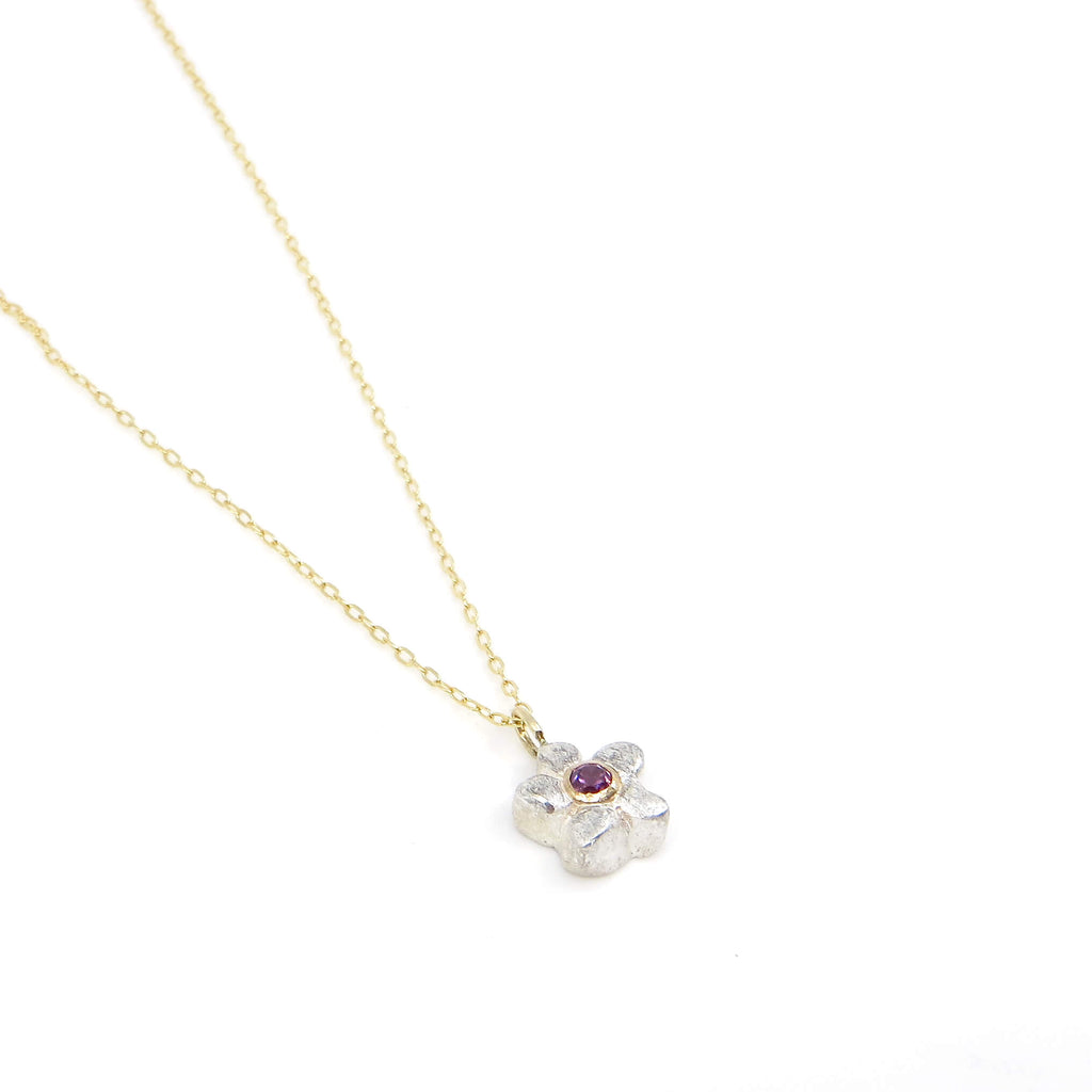 A sweet, petite chunky sterling silver flower has a lavender garnet in the center set in 14k gold. A 14k gold bail suspends the pendant from a 16" gold filled delicate chain.
