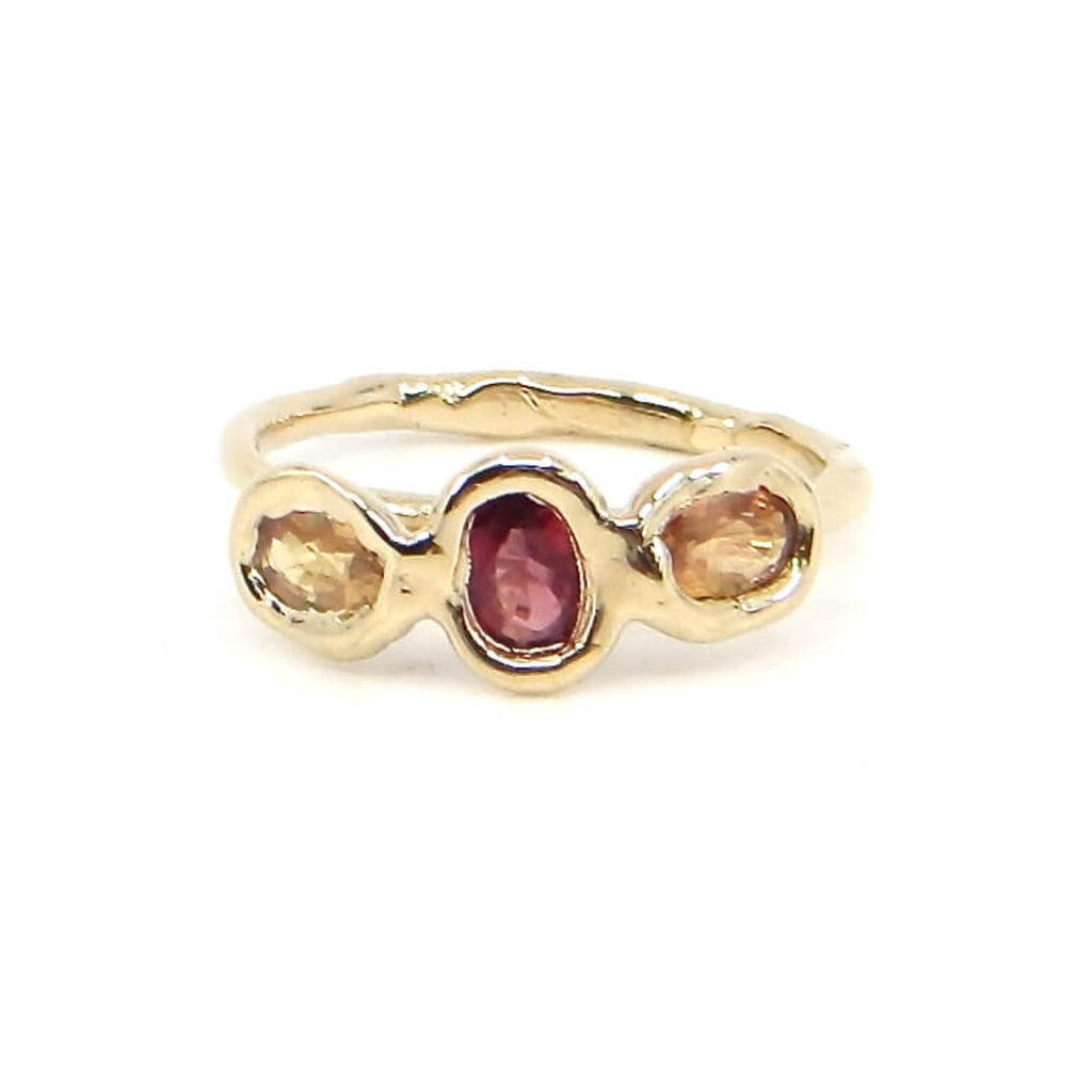 Gold and 3 oval sapphire ring. Peach side sapphires and center dark red sapphire. Organic feel shaped gold ring band and settings.  Sapphires float above ring band. US size 5.5