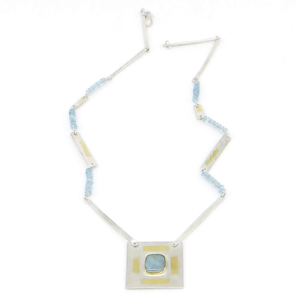Rounded square cabochon aquamarine set in 18k royal yellow gold bezel centered on  1" square matte finish sterling silver with 4 24k gold rectangles surrounding it.   Pendant is suspended from chain of faceted aquamarine beads, hammered sterling thin rectangle links, and rectangular textured links embellished with 24k gold.  17" long with  1" square pendant.