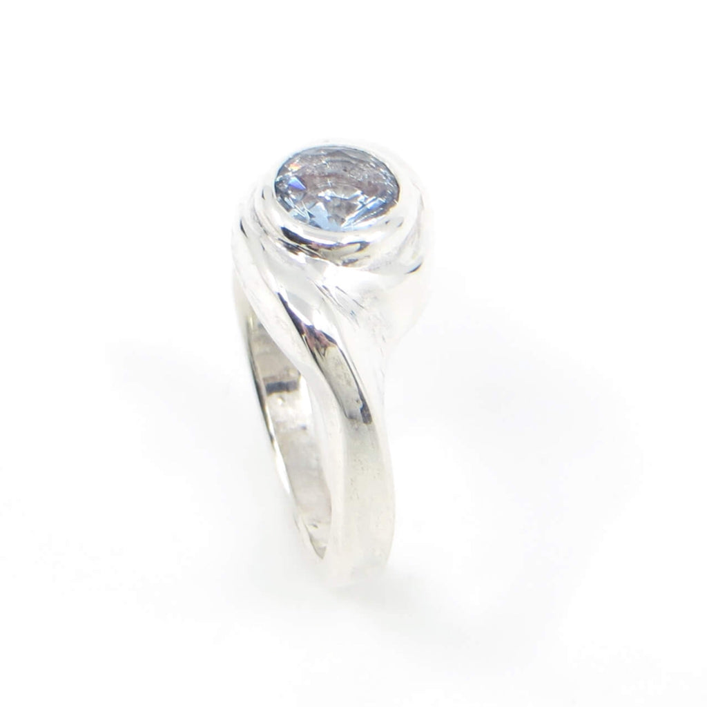 Curvilinear sterling silver ring with 6mm sparkling light blue topaz. US Size 6-6.25