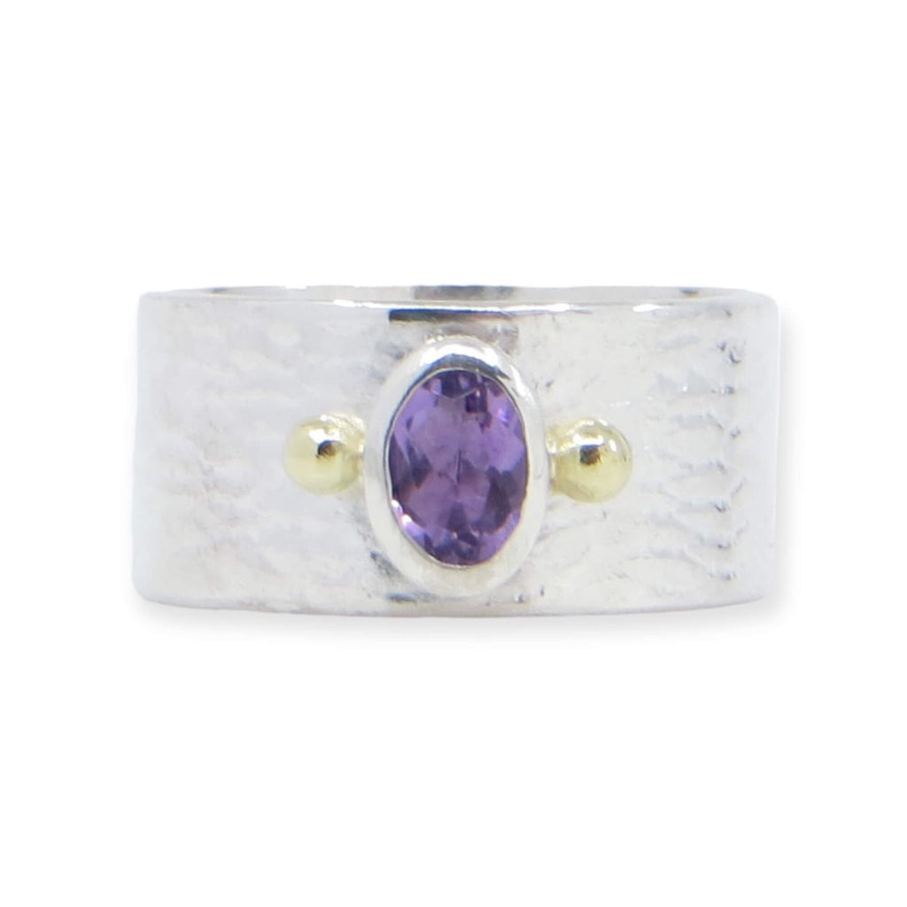 An oval faceted amethyst set between two 18k gold balls on a textured sterling wide ring. US size 7.