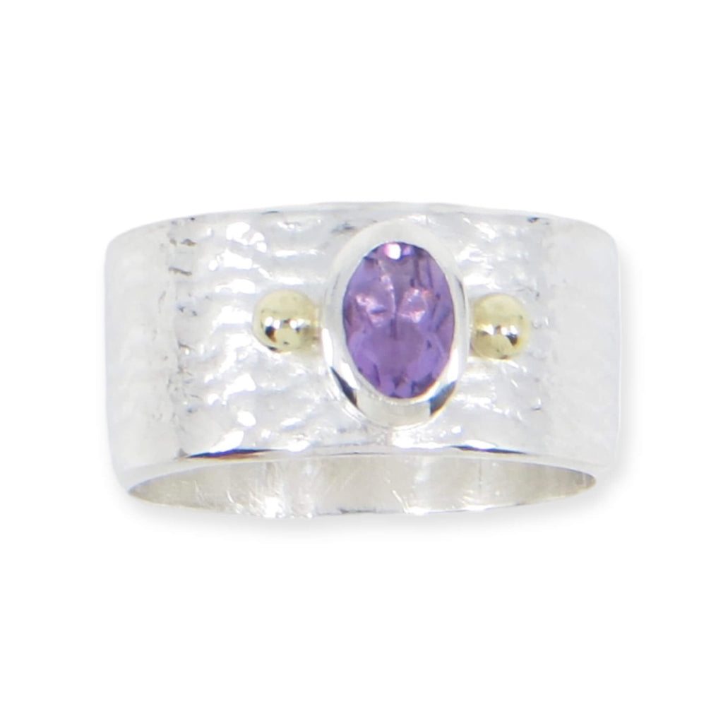 An oval faceted amethyst set between two 18k gold balls on a textured sterling wide ring. US size 7.